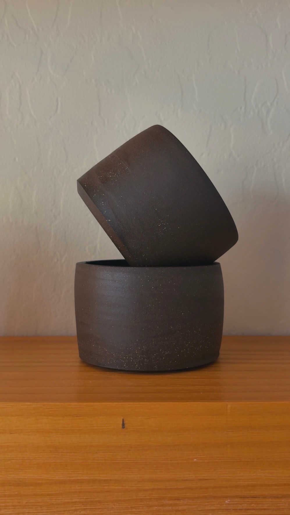 Two dark ceramic cups stacked at an angle